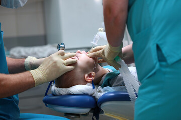 Obraz na płótnie Canvas A breathing tube is inserted into the boy. Preparing for surgery. The child is under anesthesia. Treatment of multiple caries. Operation in the dental clinic.