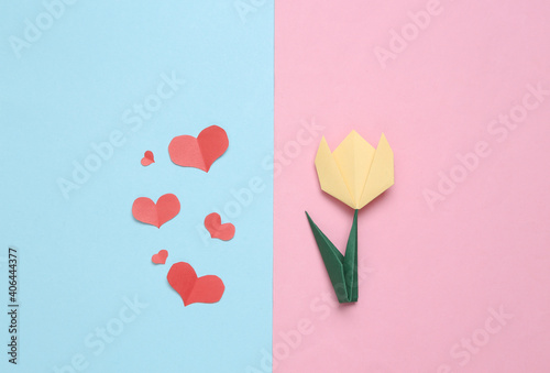 Handmade origami paper tulip and paper cut hearts.on pink blue background. 8 March or mother's day concept. Top view. Minimalism