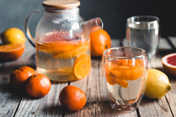 Citrus tea in a transparent teapot on a table with grapefruit and on a wooden table. Healthy drink.