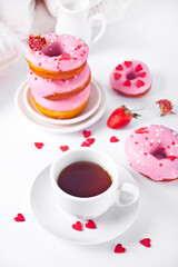 Cup of coffee and pink doughnuts on the white background. Valentine's Day concept.
