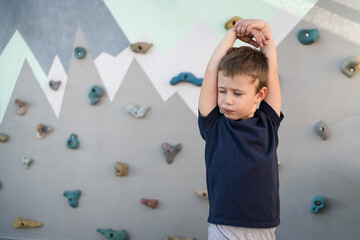 Niño estirando antes de hacer escalada en el rocódromo