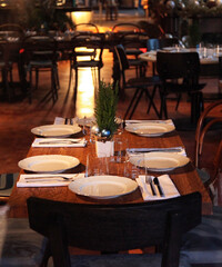 Christmas table in the cafe, white plates, wooden chairs.