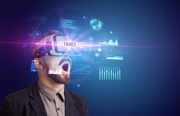 Businessman looking through Virtual Reality glasses with TAXES inscription, new business concept