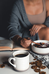 Healthy winter breakfast . Woman in woolen sweater and shabby jeans eating vegan almond milk oatmeal porridge with berries, fruit and almonds. Clean eating, vegetarian food concept