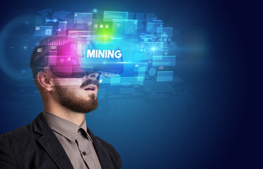 Businessman looking through Virtual Reality glasses with MINING inscription, innovative security concept
