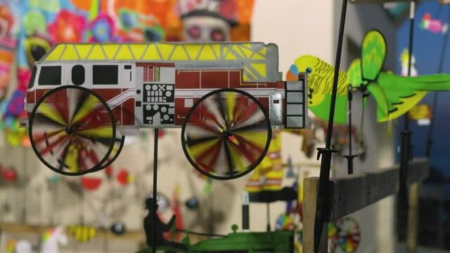 Firetruck pinwheel spinning in the wind at a kiosk on a California pier. Footage captured in slow motion.