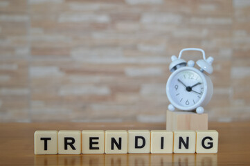 Selective focus with noise effect of clock and scrabble letters with text TRENDING. Business  concept.