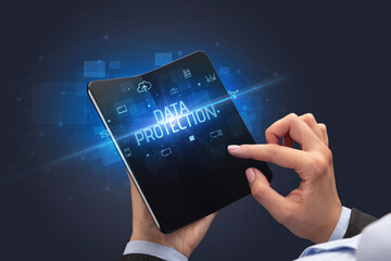 Businessman holding a foldable smartphone with DATA PROTECTION inscription, cyber security concept