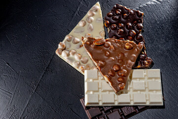 Three types of chocolate - black, milk and white on a black background with copy space