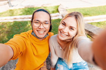 Multiracial couple wearing protective face mask taking a selfie outdoor - New normal friendship concept with young people having fun outdoor - Bright filter