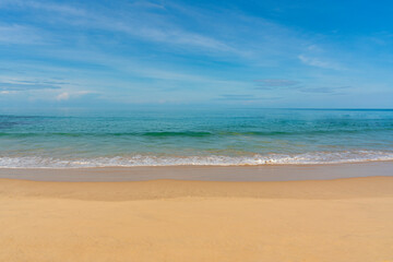 Fototapeta na wymiar View of blue sky, blue sea, small wave and yellow sand that is signature of beautiful seascape scene at Phuket Province, Thailand in the morning of holiday.