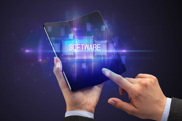 Businessman holding a foldable smartphone with SOFTWARE inscription, new technology concept