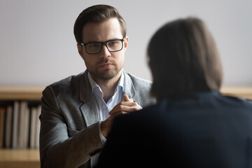 Concentrated male hr manager in glasses listening to job candidate, involved in conversation during...