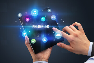 Businessman holding a foldable smartphone with INFLUENCER inscription, social media concept