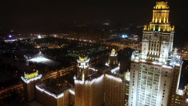 Aerial Shot of Lomonosov Moscow state university in winter at night, MSU foreground, Moscow city backdrop
