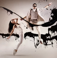 Foto op Canvas Fashion style portrait of young dancers jumping into the paint splash © konradbak