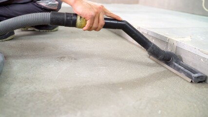 Cleaning of construction waste with a vacuum cleaner. Worker vacuuming debris and dust from floor after drilling concrete wall. A worker vacuums the concrete floor.