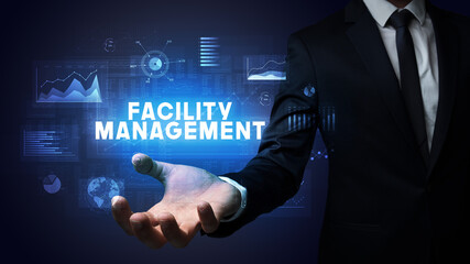 Hand of Businessman holding FACILITY MANAGEMENT inscription, business success concept