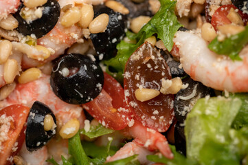 Vegetable salad with prawns and pine nuts on a plate. Homemade food. Close up.