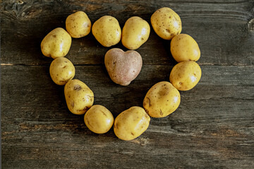 Heart shaped red potato inside heart lined with white potatoes on wooden background.The concept of...