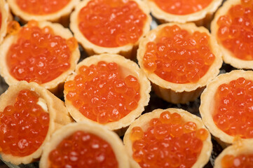 Tartlets with salmon caviar on a platter. Close-up, selective focus.