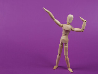 Wooden puppet mannequin posing on a purple background.
