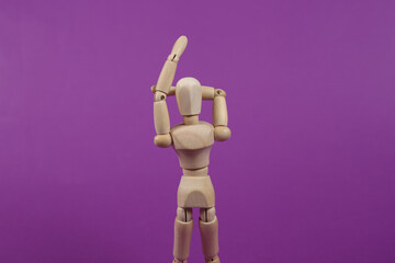 Wooden puppet practices hand stretching against a purple background. Healthy lifestyle concept