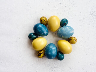 painted Easter eggs (yellow, blue) on white background , top view