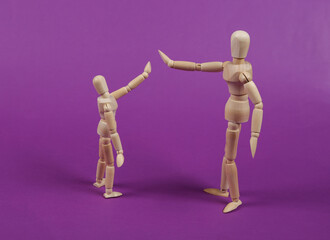 High five. Two wooden puppets on a purple background.