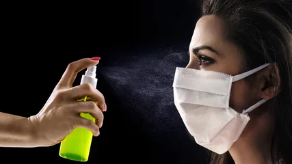 Foto op Canvas Conceptual portrait of a woman wearing hygienic mask and looking at the antibacterial spray © konradbak