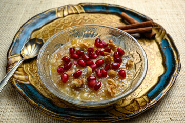 Ashure or Noah's pudding, the turkish dessert porridge in glass bowl on golden dish