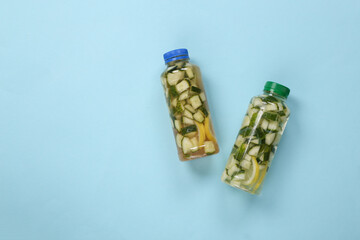 Detox drink, cucumber lemonade bottles on blue background. Top view.