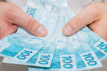 Brazilian Real. Money spread out in a fan, held in a man's hand