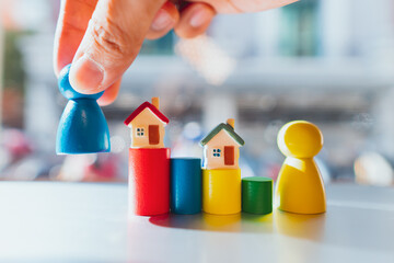 Miniature house on colorful wooden block with hand hold people symbol using as property real estate...
