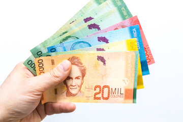 Costa Rican money, Colones, Banknotes spread out in a fan and held in a male hand, White background