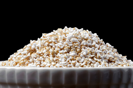 airy grains of amaranth in a white plate on a black background close-up