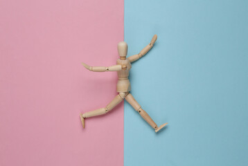 Happy wooden puppet mannequin on a pink blue background. Top view