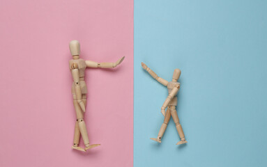 High five. Two wooden puppets on pink blue pastel background. Top view