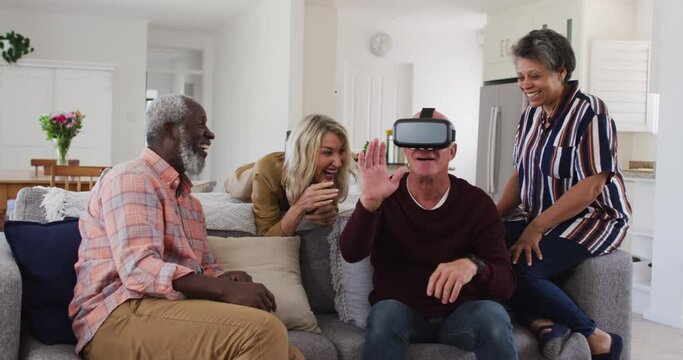Two diverse senior couples sitting on a couch caucasian man is using vr googles