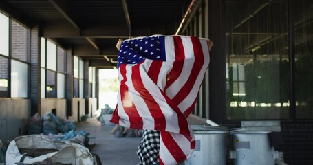 Mixed race woman holding us flag running through an empty building