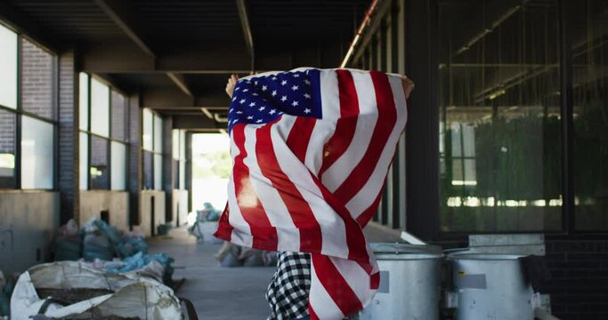 Mixed race woman holding us flag running through an empty building