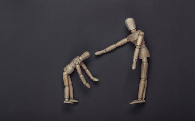 Wooden puppet scolds child puppet on gray background