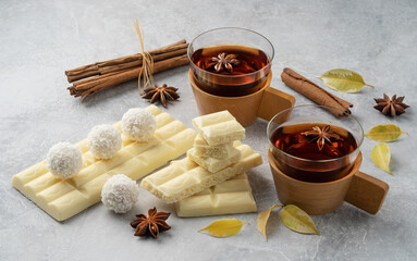 Pieces of white chocolate on a light gray table, with two pieces of fragrant tea.