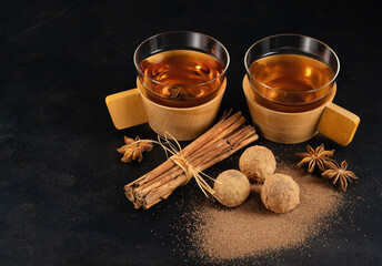 Two glass cups with black fragrant tea with truffle chocolates on a dark background.