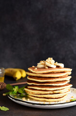 Homemade pancakes with banana and pine nuts on a dark background