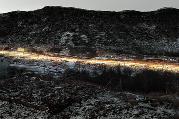 Empty winter evening arctic road between the hills on a polar night.
