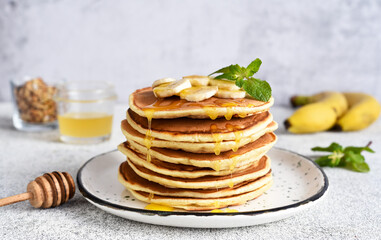 Homemade pancakes with banana, honey and mint on the kitchen table.