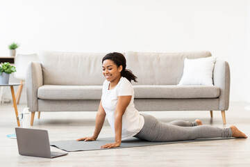 Black woman exercising at home watching online tutorial on laptop