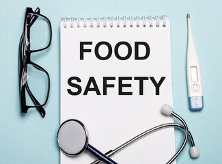 FOOD SAFETY written on a white notepad next to a stethoscope, goggles, and an electronic...