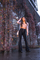 Fototapeta premium Young pretty Caucasian brunette walking in the city in winter, wearing a pink wool sweater. Street style fashion